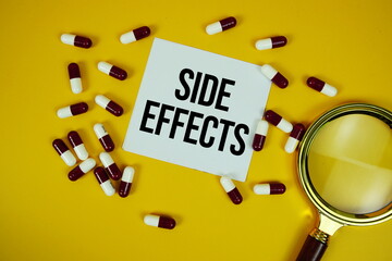 Side Effects text on sticky note paper with Medicine capsule and Maginfying glass on yellow...