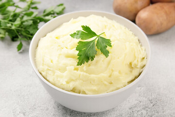 Mashed potatoes in white bowl on grey concrete background. Healthy food