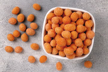 Spicy coated fried peanuts on gray background. Snacks and nuts.