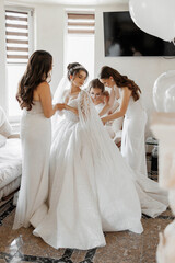 A bride is getting ready for her wedding with her bridesmaids. The bride is wearing a white dress...