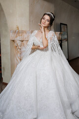 Fototapeta premium A woman in a white gown with a tiara on her head. She is posing for a picture