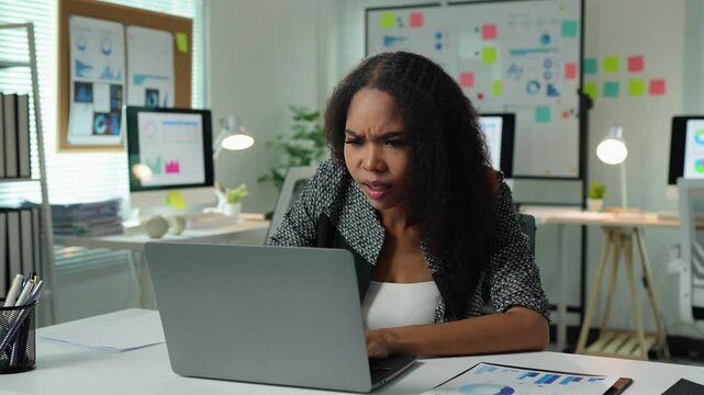 African American businesswoman looking at laptop, stressed while looking at report on business growth data sheet or email with online problems, financial errors, corrections in company system.