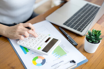 Woman is using a calculator to calculate information on a document