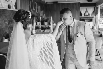 A bride and groom are kissing each other's foreheads. The bride is wearing a white veil and the groom is wearing a suit
