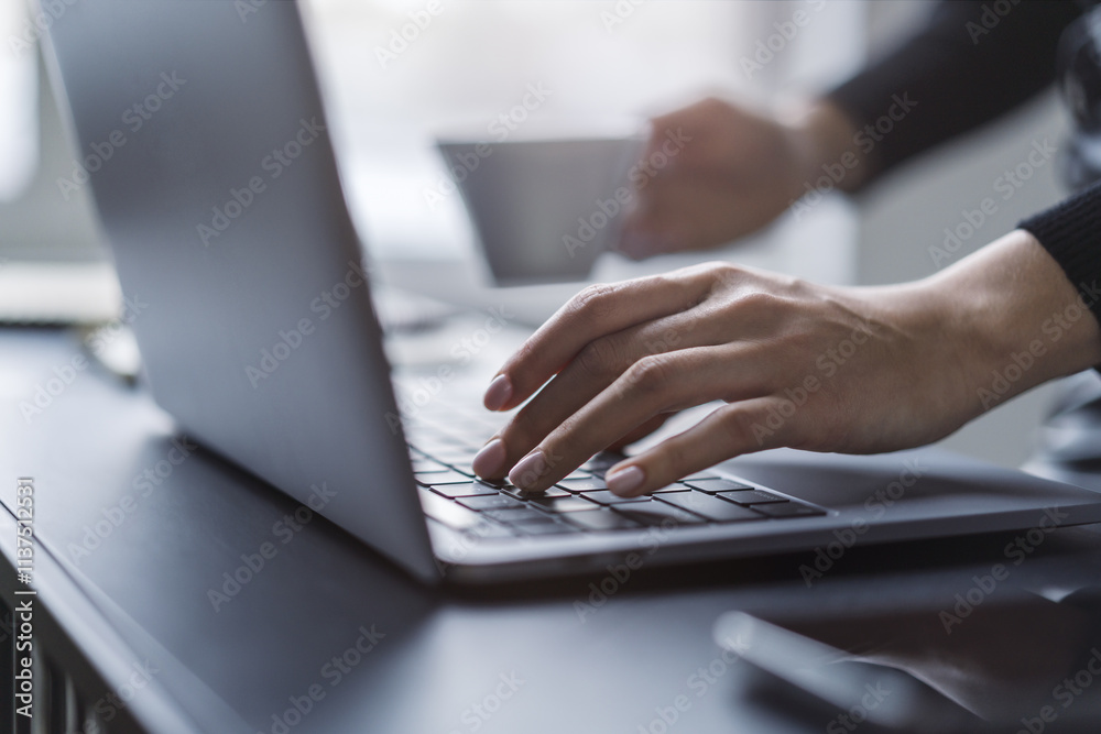 Poster Female hands in sharp focus typing on a modern laptop keyboard, office environment in soft blur behind