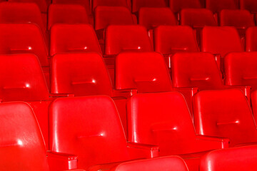 A row of red chairs are empty in a theater