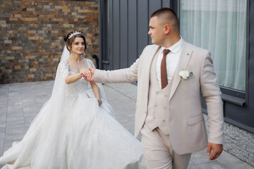 Fototapeta premium A bride and groom are walking down a street, the bride is wearing a white dress and the groom is wearing a suit