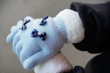 小学生の女の子向けの水色リボン付き手袋を、11歳の女の子が身につけている様子。