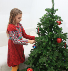 Mädchen schmückt Weihnachtsbaum