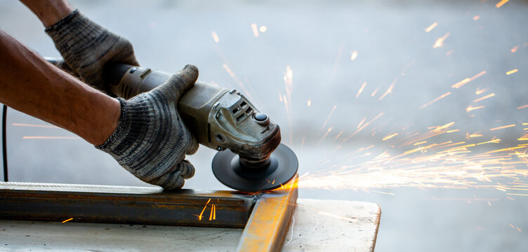 Grinding machine at work. Sparks fly from under the grinders, men's work. Dark background with copy space.