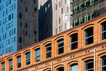 An image showing the striking contrast between an old brick building and sleek modern architecture, symbolizing the blend of traditional and contemporary urban development in Barcelona Spain