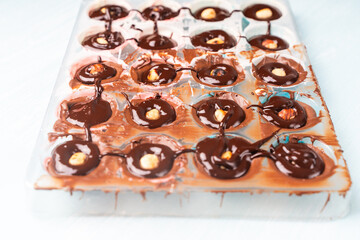 The nut mold is filled with tempered chocolate and ganache. The process of making homemade chocolates.