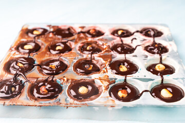 The nut mold is filled with tempered chocolate and ganache. The process of making homemade chocolates.
