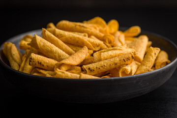 Rolled nachos tortilla chips on plate on black table.