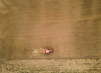 Aerial photography of  a medium-sized orange tractor is plowing the agricultural field to prepare for planting.