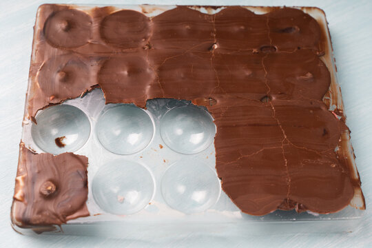 The mold for making chocolate candies is filled with solidified chocolate and finished candies in pink glaze. Homemade chocolate recipe.