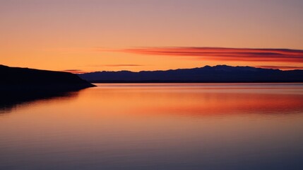 Fototapeta premium Serene sunset over calm waters, reflecting vibrant colors and distant mountains.