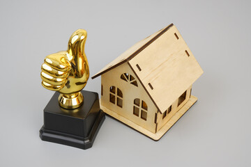 Gold thumbs up  house model on gray background. Best real estate concept.