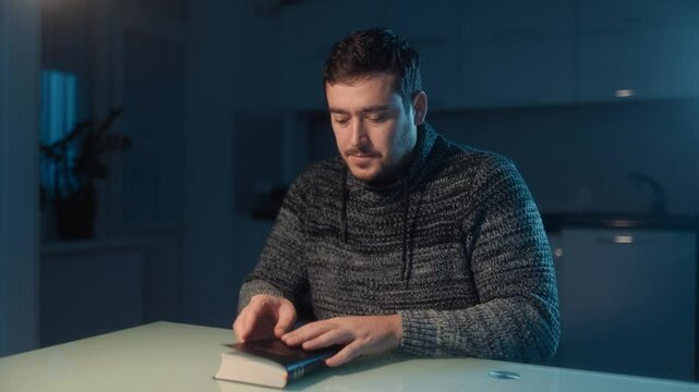 Religious man in a cozy setting prays after finishing Bible reading.