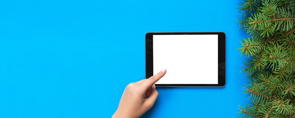 people and technology concept, close up of female hands pointing finger to tablet. blank screen on blue background, top view