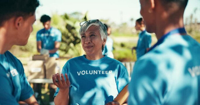Outdoor, people and discussion with clipboard for volunteering, community service or charity program. Park, mature coordinator or team with checklist for donation, ngo conversation or welfare project