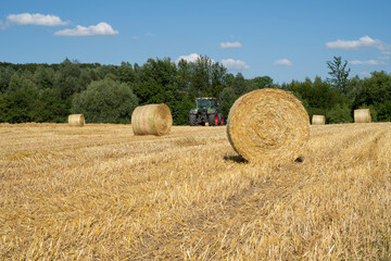 Strohballen und Trecker auf abgeerntetem Kornfeld, Stoppelfeld, Kamen. Nordrhein-Westfalen, Deutschland, Europa