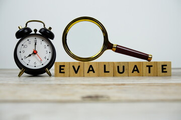 Time to Evaluate with wooden blocks alphabet letters and Magnifying glass on wooden background