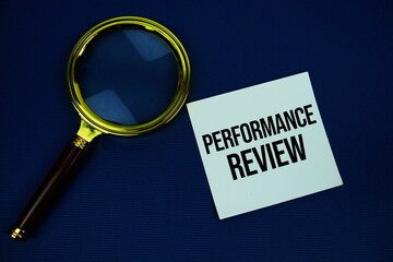 Proformance Review text on speech bluble with magnifying glass top view on navy blue background