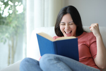 Excited asian woman celebrating book argument at home