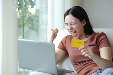 Fototapeta premium Excited asian woman buying online with laptop and card
