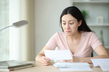 Perplexed asian woman checking bill