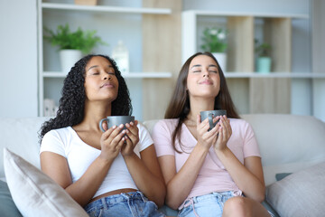 Two friends breathing drinking coffee relaxing at home