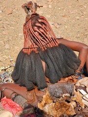 Himba woman lying on the ground showing her elaborate ochre and hair hairstyle, with traditional...