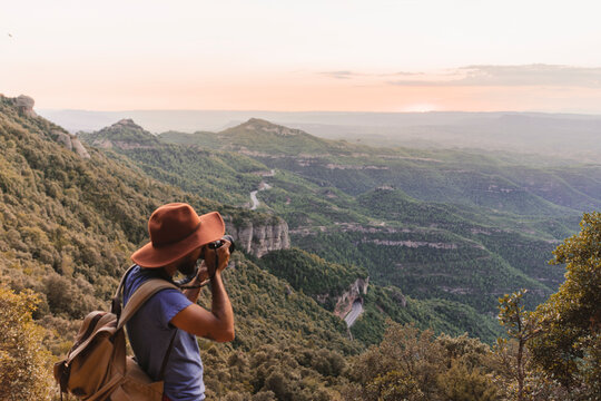 Spain, Barcelona, Montserrat, man with backpack taking photo of view at sunset