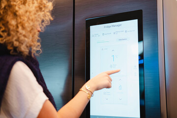 Young woman using automated refrigerator