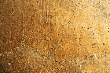 Old worn gold colored wall as grunge texture