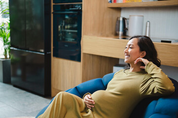 Smiling pregnant woman sitting on sofa at home