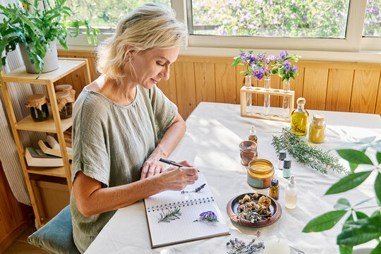 Woman writing recipe in notebook at table