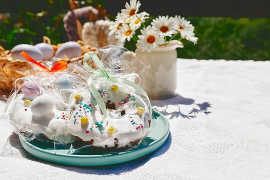 Decorated Easter doughnuts near eggs and flower vase on sunny day