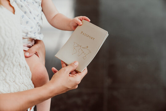 Hand of woman and baby girl holding passport at airport