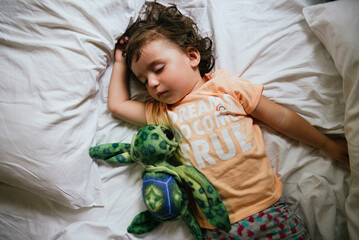 Baby girl sleeping on bed with t-shirt message 'Dreams do come true'