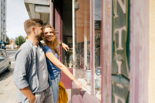 Belgium, Tongeren, happy young couple at shop window of an antique shop