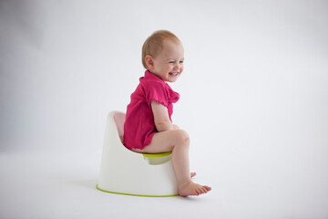 Laughing baby girl sitting on potty