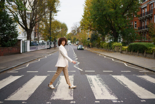 Curly haired businesswoman crossing Abbey road in London city, England, UK