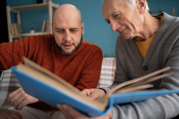 Grandfather and grandson spent time together looks photo with elderly parent, family members through the pages of the album