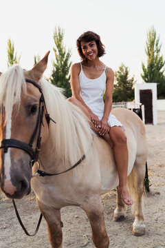 Portrait of happy woman sitting bareback on horse