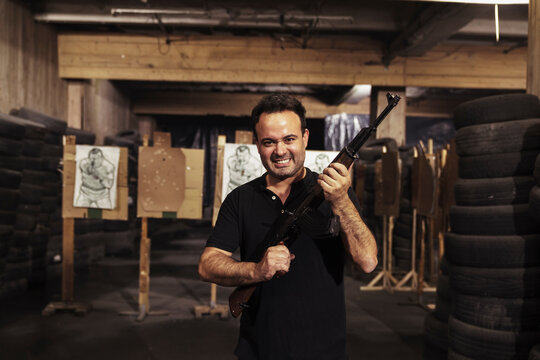 Portrait of aggressive man holding a rifle in an indoor shooting range