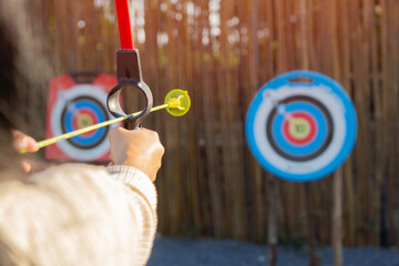 Back view of woman practicing or playing soft archery on the training field