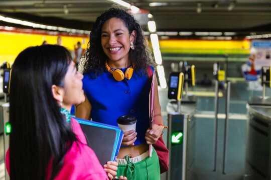 Happy friends talking and standing at subway station