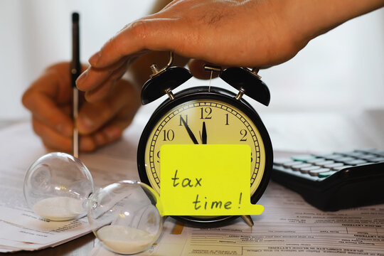Tax Time Concept: Deadline Reminder with Alarm Clock, Papers, and Sand Timer Setup
